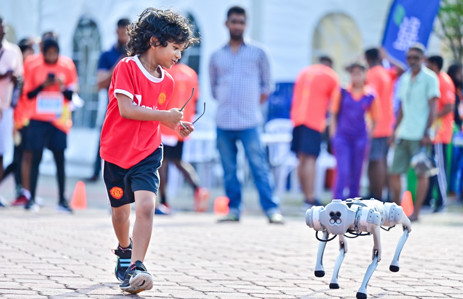 ރޯޑް ރޭސް ކުރިއަށް ދިޔައިރު އެ ސަރަހައްދުގައި ބޭނުންކުރަމުން ދިޔަ ރޮބޮޓްއެއް ކައިރީގައި ކުޑަކުއްޖަކު ހަރަކާތްތެރިވަނީ -- ފޮޓޯ؛ ފަޔާޒު މޫސާ | މިހާރު