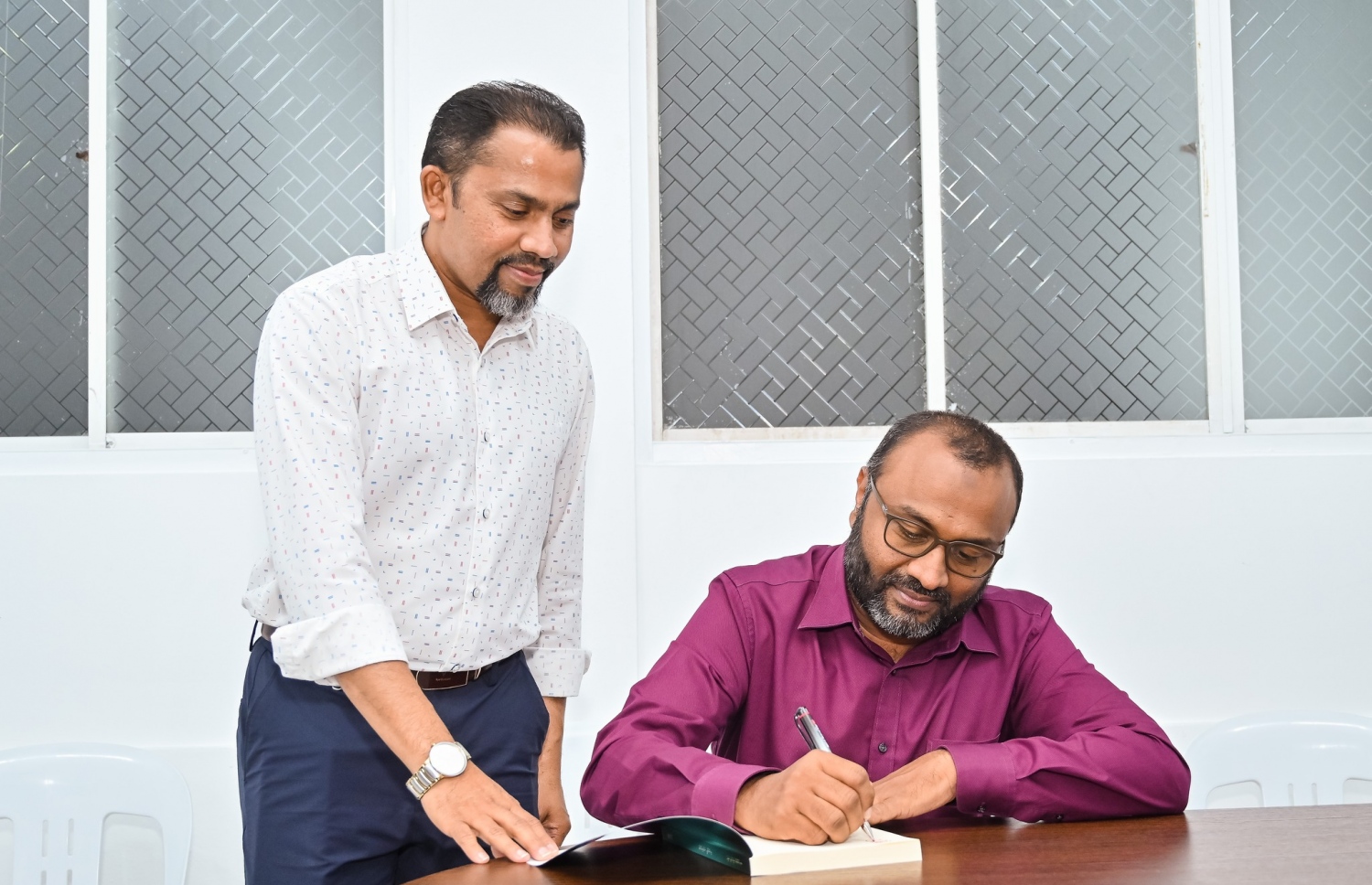 އިސްލާމީ ނަޒަރިއްޔާތު ފޮތް ނެރެދެއްވުމަށް ފަހު، އެވިޑް ކޮލެޖުގެ ޗެއާމަން މުޝްތާގްގެ ފޮތުގައި ޝަހީމް ސޮއިކުރައްވާއިރު އަރިހުގައި މުޝްތާގް މަޑުކޮށްލައްވައިގެން.---ފޮޓޯ: ނިޝާން އަލީ| މިހާރު