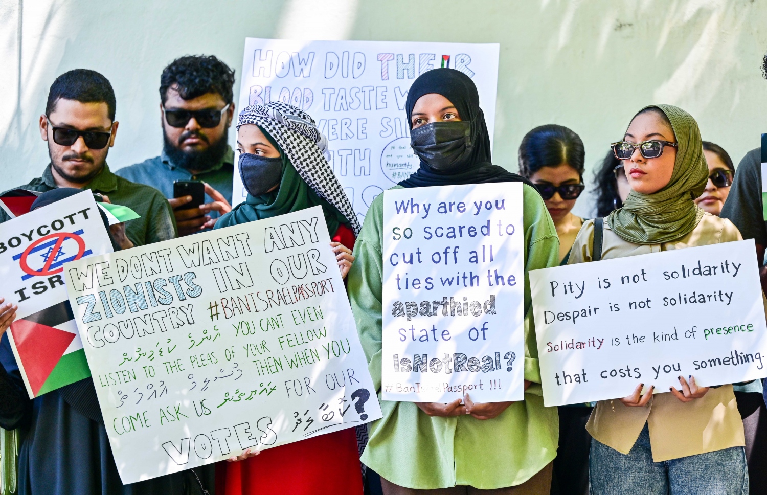 އިޒްރޭލުން ފަލަސްތީނުގެ މީހުންނާ ދެކޮޅަށް ހިންގާ ލާއިންސާނީ އަމަލުތައް ކުށްވެރިކޮށް، އެ ގައުމުގެ ޕާސްޕޯޓްގައި ރާއްޖެ އަށް ނާދެވޭ ގޮތް ހެދުމަށް ގޮވާލައި ޕްރެޝަރު ކުރުމަށް މިއަދު ރައްޔިތުންގެ މަޖިލީހުގެ އިދާރާ ކުރިމަތީ ބޭއްވި އިހުތިޖާޖުގެ ބައެއް ބައިވެރިން.--- ފޮޓޯ: ފަޔާޒު މޫސާ / މިހާރު