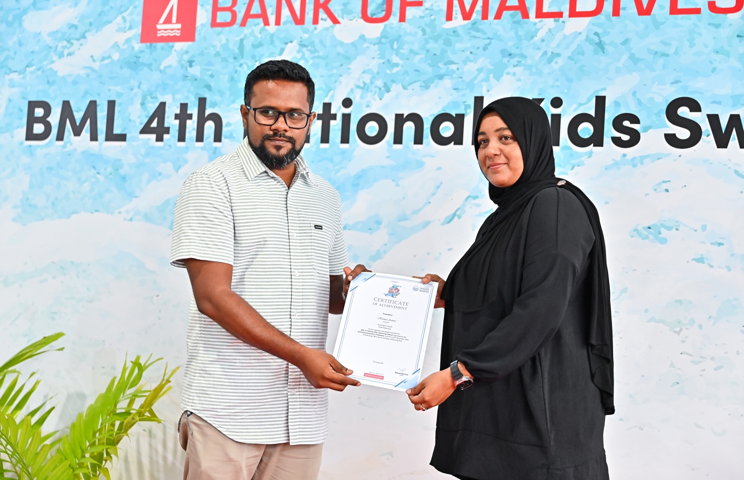 ހަތަރުވަނަ ބީއެމްއެލް ނެޝެނަލް ކިޑްސް ސުވިމިން ފެސްޓިވަލުގައި ބައިވެރިވި ޓީމަކަށް ހަނދާނީ ލިޔުން ހަވާލުކުރަނީ.--- ފޮޓޯ: ފަޔާޒު މޫސާ | މިހާރު