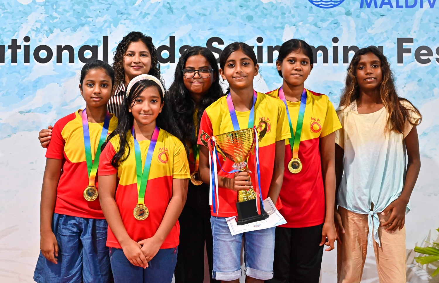 ބީއެމްއެލް ނެޝެނަލް ކިޑްސް ސުވިމިން ފެސްޓިވަލްގައި ބައިވެރިވެ، ވަނަ ހޯދި ޓީމަކުން ތައްޓާ އެކު ފޮޓޯއަކަށް ހުއްޓިގެން.--- ފޮޓޯ: ފަޔާޒު މޫސާ | މިހާރު