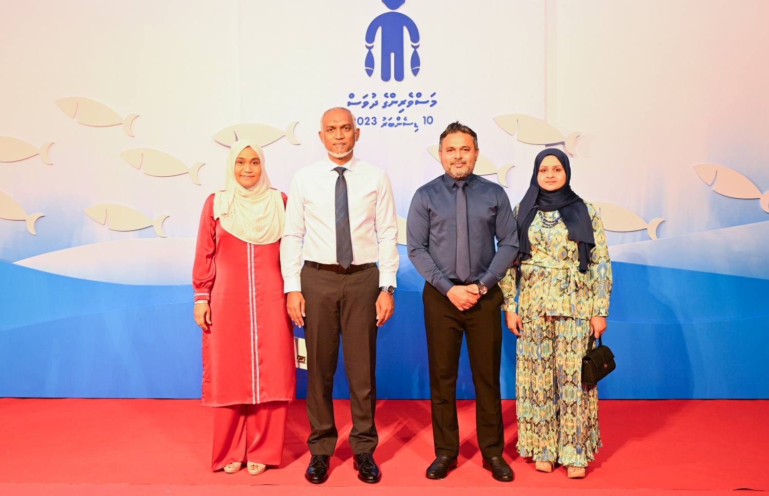 މަސްވެރިންގެ ދުވަހުގެ ޖަލްސާގައި ރައީސް ޑރ މުހައްމަދު މުއިއްޒު އާ ފިޝަރީޝް މިނިސްޓަރު އަހުމަދު ޝިޔާމް ފޮޓޯއަކަށް ހުއްޓިލައިގެން -- ފޮޓޯ: ރައީސް އޮފީސް