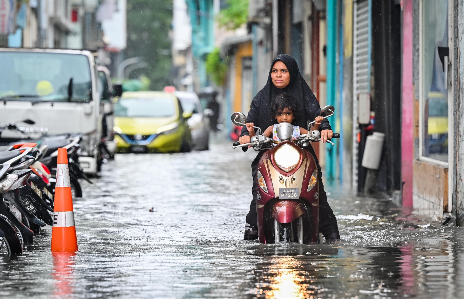 ރެއިން ފެށިގެން މާލެއަށް ކުރަމުންދާ ގަދަ ވިއްސާރައިގައި، ފެންބޮޑުވެފައި މަގަކުން މީހަކު ކުޑަ ކުއްޖެއްގޮވައިގެން ސައިކަލުދުއްވާފަ ދާން މަސައްކަތްކުރަނީ.-- ފޮޓޯ: ނިޝާން އަލީ / މިހާރު