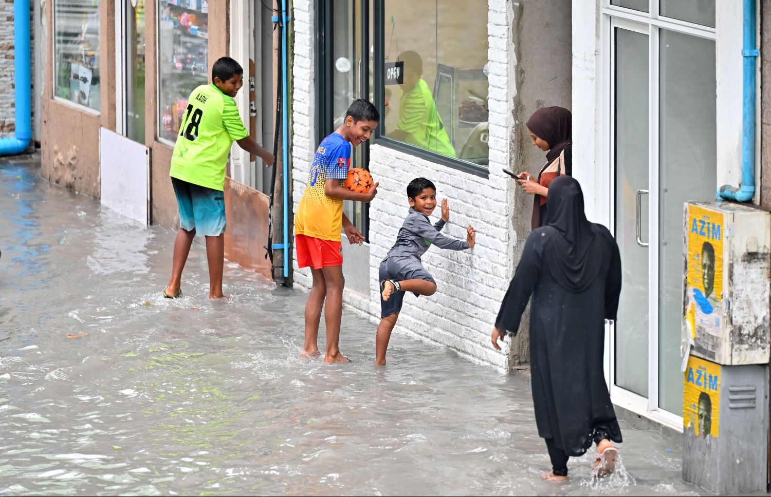 ފެން ބޮޑުވެފަ ވާ މަގެއްގައި ކުޑަ ކުދިންތަކެއް ހަރަކާތްތެރިވަނީ: ރެއިން ފެށިގެން މާލެއަށް ކުރަމުންދާ ގަދަ ވިއްސާރައިގައި، މާލޭގެ ގިނަމަގުތައް ވަނީ ފެންބޮޑުވެފައި.-- ފޮޓޯ: ނިޝާން އަލީ / މިހާރު