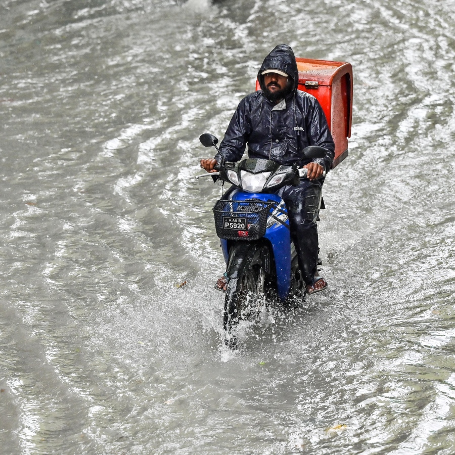 ރެއިން ފެށިގެން މާލެއަށް ކުރަމުންދާ ގަދަ ވިއްސާރައިގައި ފެންބޮޑުވެފައި މަގަކުން މީހަކު ވާރޭ ކޯޓުލައިގެން، ސައިކަލްގައި ދަނީ.-- ފޮޓޯ: ނިޝާން އަލީ / މިހާރު