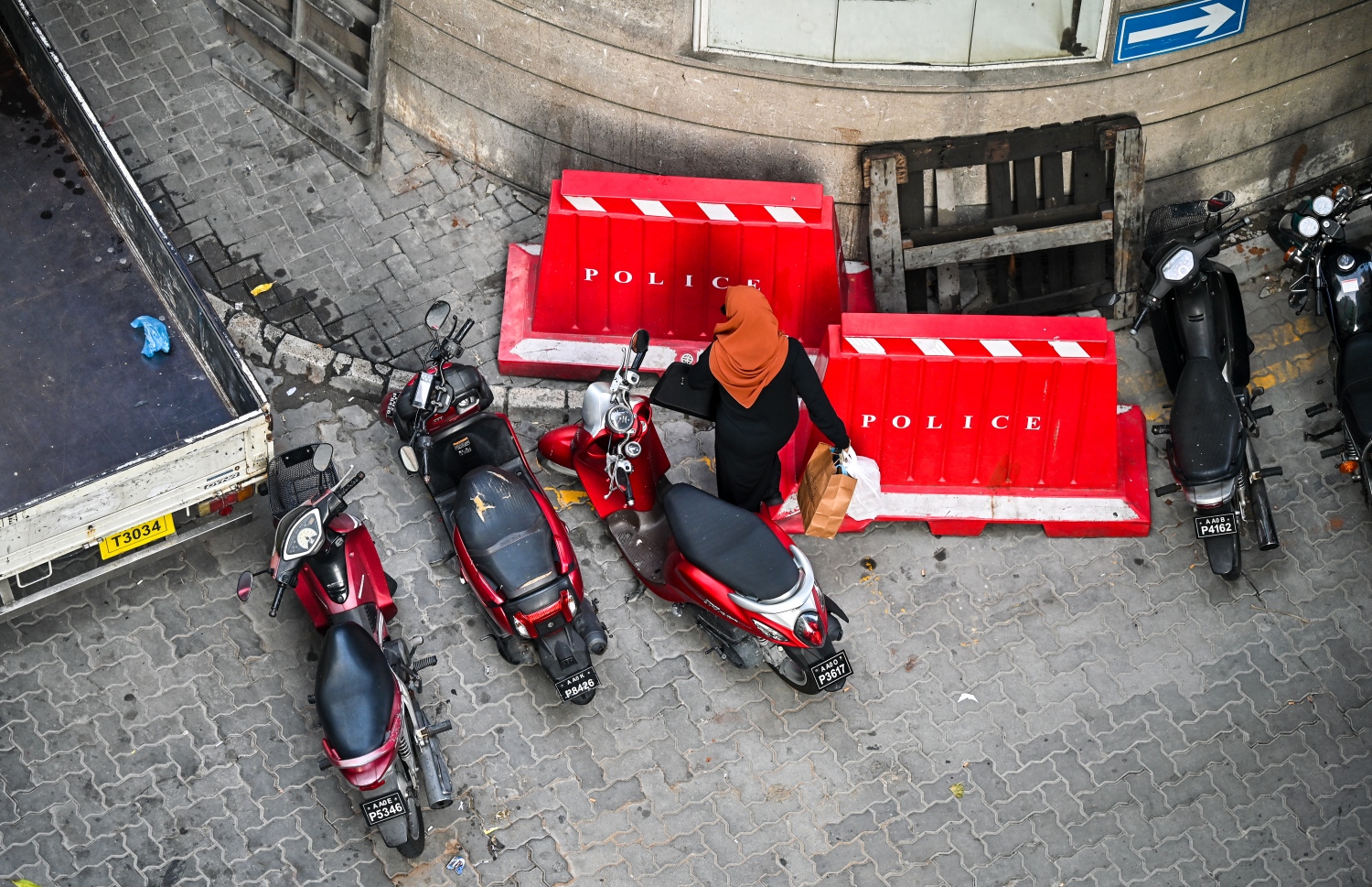 ގަވާއިދާ ހިލާފަށް ޕާކްކޮށްފައި ހުރި ސައިކަލްތަކެއް ކައިރިން މީހަކު ޕޭމަންޓަށް އަރަން މަސައްކަތްކުރަނީ -- ފޮޓޯ؛ ފަޔާޒު މޫސާ | މިހާރު