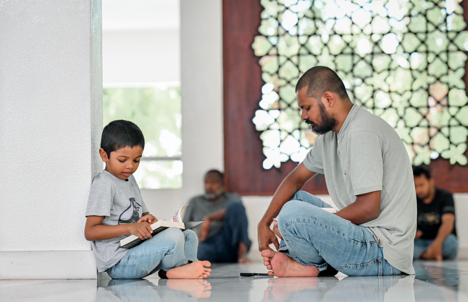 އިސްލާމީ މަރުކަޒުގައި މިއަދު ކުރި މެންދުރު ނަމާދަށް ފަހު ކުޑަކުއްޖަކާއި އެ ކުއްޖާގެ ބެލެނިވެރިޔާ ގުރުއާން ކިޔަވަނީ.---ފޮޓޯ: ނިޝާން އަލީ| މިހާރު