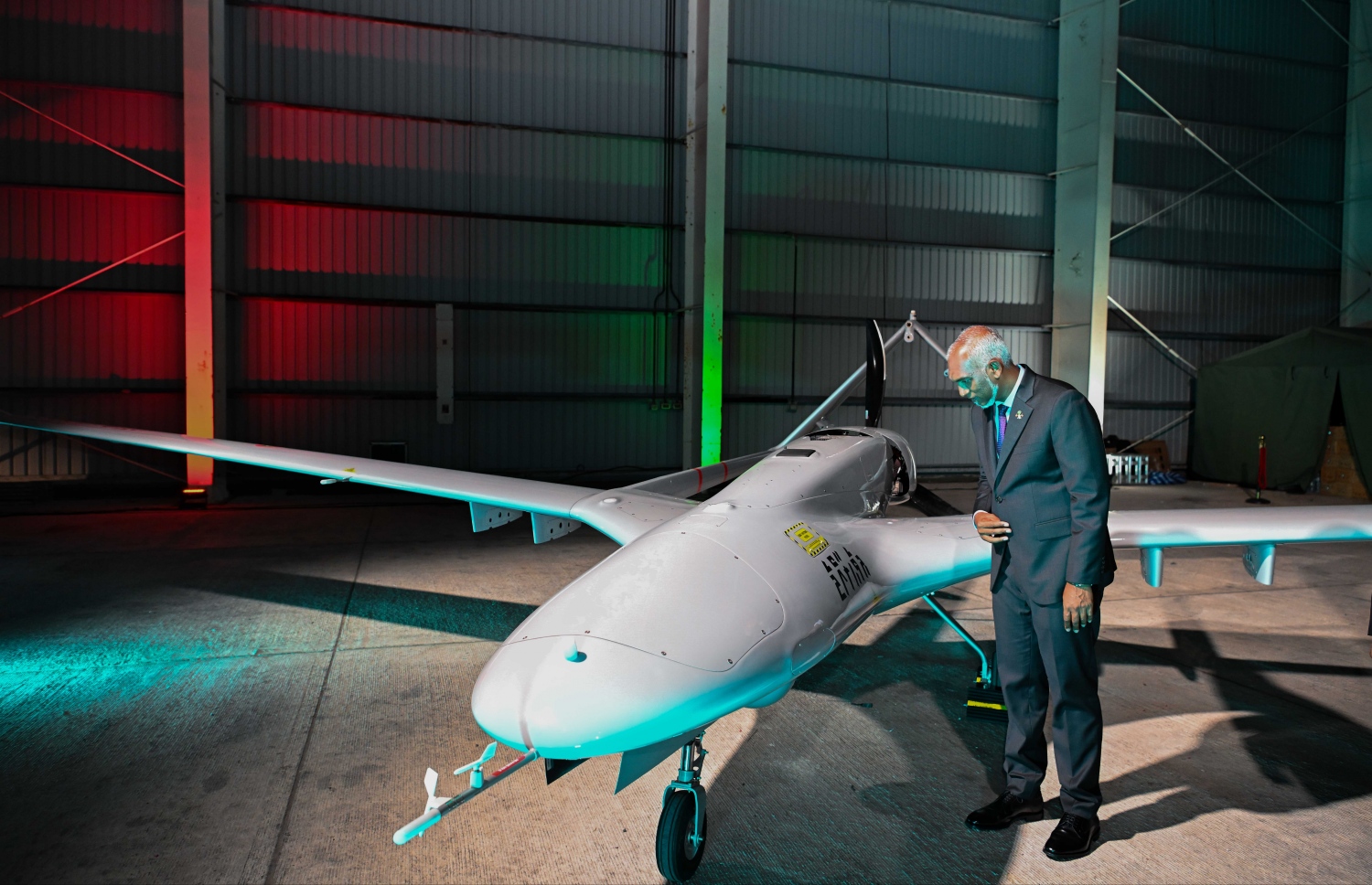 ރާއްޖޭގައި ފުރަތަމަ އަސްކަރީ ޑްރޯންތައް ބޭނުންކުރަން ފެށުމަށް މިދިޔަ ހުކުރު ދުވަހުގެ ރޭ މާފަރު އިންޓަނޭޝަނަލް އެއާޕޯޓުގައި ބޭއްވި ރަސްމިއްޔާތުގައި ރައީސް މުއިއްޒު ތިން ޑްރޯން އިން އެއް ޑްރޯންގައި ދިވެހި ތާނައަކުރުން ލިޔެފައިވާ ރާއްޖޭގެ ނަން ބައްލަވާލައްވަނީ.---ފޮޓޯ: ރައީސް އޮފީސް