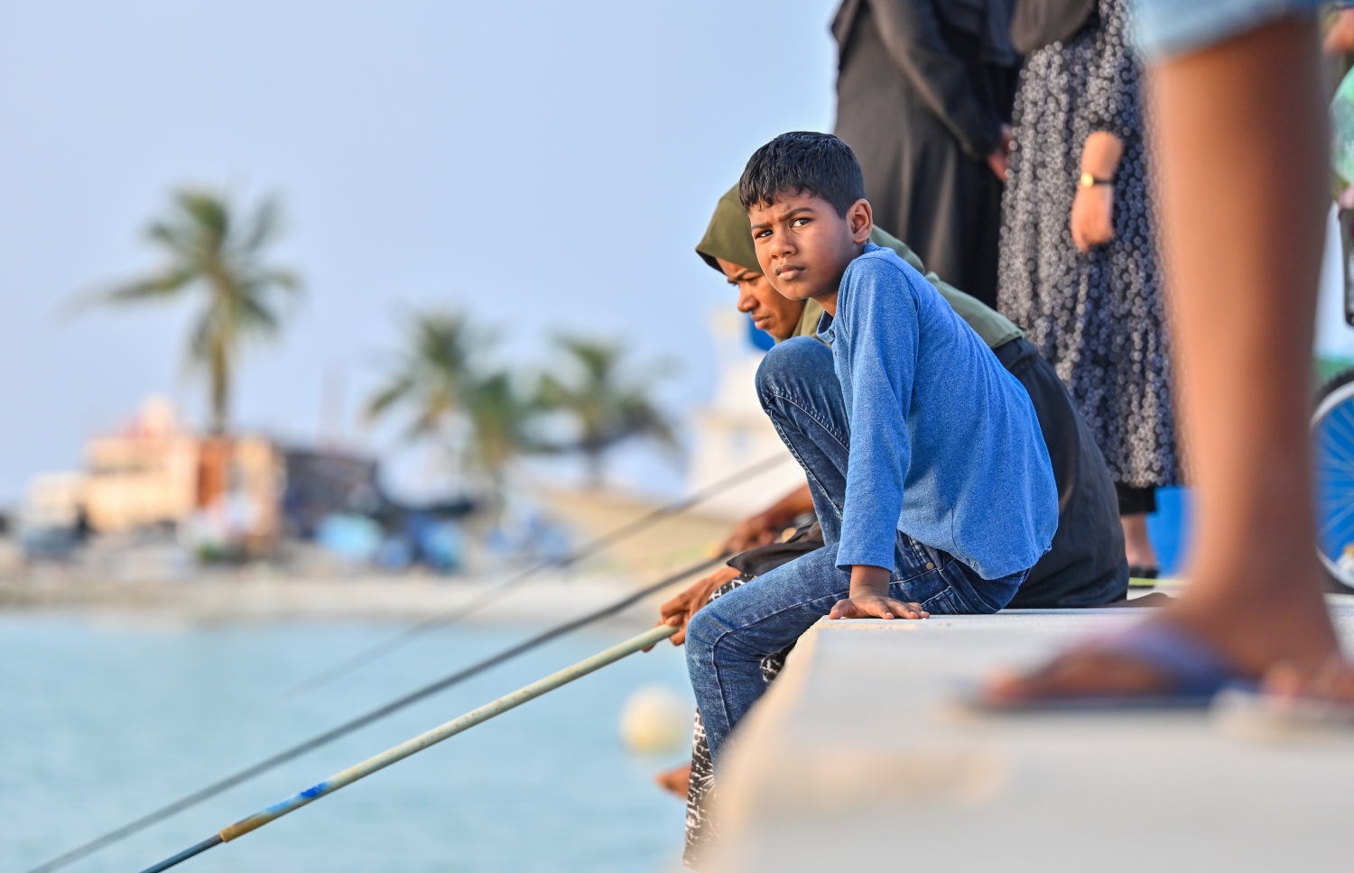 ކުޑަކުދިންތަކެއް އެ ކުދިންގެ ބެލެނިވެރިންނާ އެކު ރަށުގެ ބަނދަރު ސަރަހައްދުގައި މުށިމަސް ބާނަނީ. -- ފޮޓޯ: ފަޔާޒު މޫސާ | މިހާރު