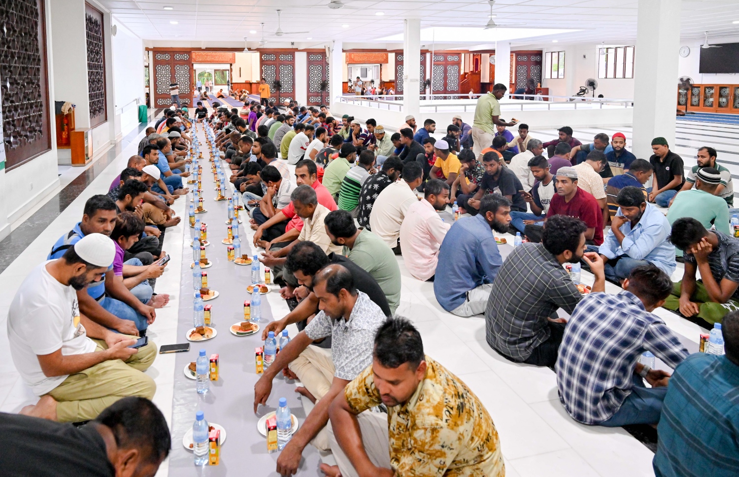 ރާއްޖޭގައި މަސައްކަތްކުރާ ގިނަ އަދަދެއްގެ ބިދޭސީ މަސައްކަތްތެރިން އިސްލާމީ މަރުކަޒުގެ ގޯތިތެރޭގައި ރޯދަ ވީއްލަން ތައްޔާރު ވެގެން، ރަމަޟާން މަހު މިސްކިތްތަކަށް ރޯދަ ވީއްލަންދާ މީހުންގެ ތެރެއިން ގިނައީ ބިދޭސީން.--- ފޮޓޯ: ނިޝާން އަލީ | މިހާރު