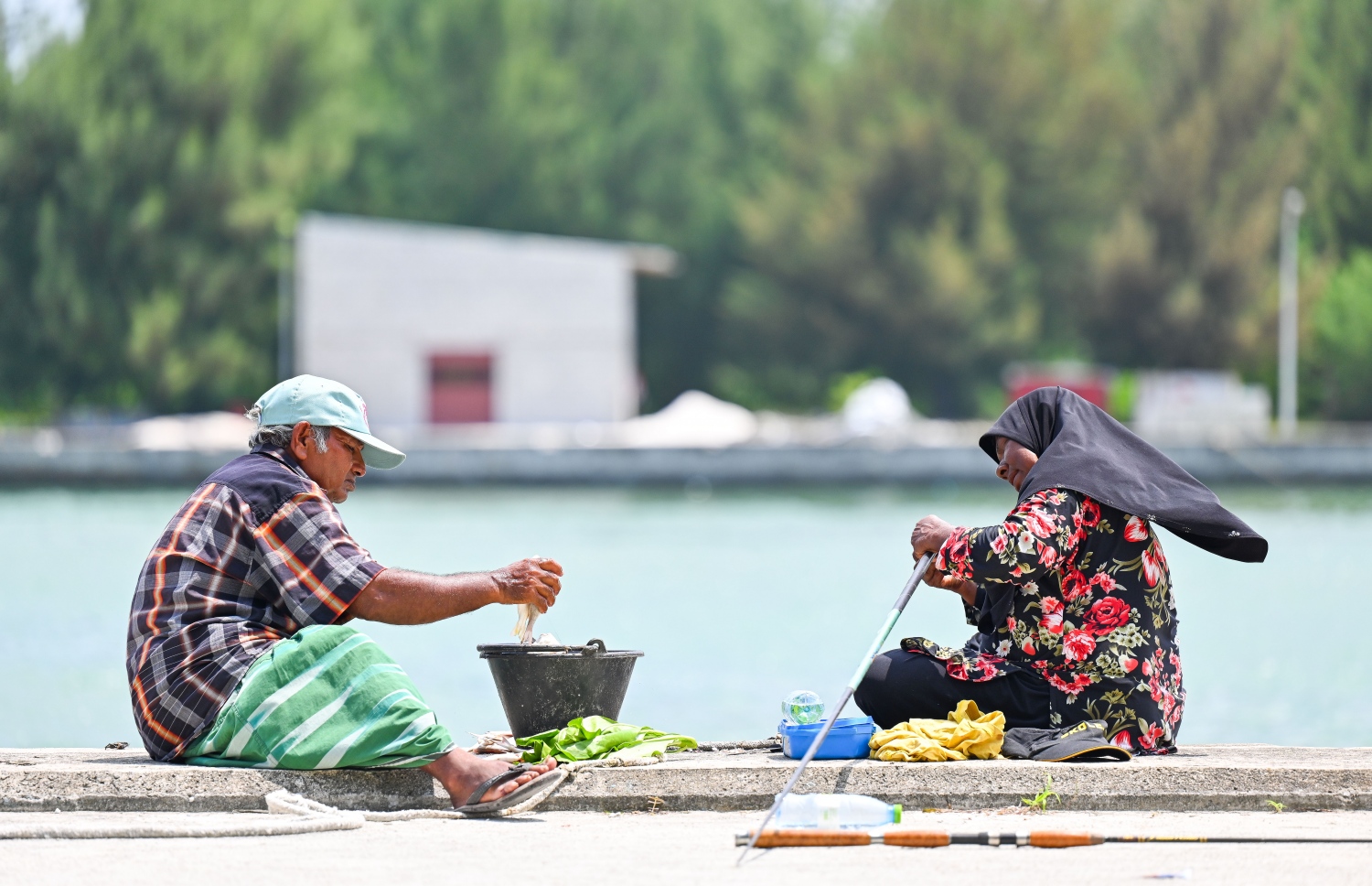 ފާތުމަތާއި އޭނާގެ ފިރިމީހާ މުހައްމަދު، މި ރަށުގެ ބަނދަރުމަތީގައި ތިބެގެން މަސް ބާނަނީ.-- ފޮޓޯ: ފަޔާޒު މޫސާ/ މިހާރު