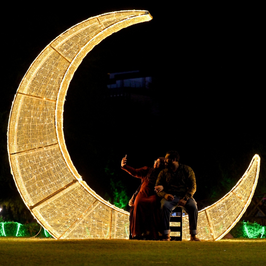 ފިތުރު އީދަށް ހުޅުމާލޭގެ އެކި ސަރަހައްދުތައް ކުލަ ބޮކިތަކާއި ޑިޒައިންތަކުން ޒީނަތްތެރިކޮށްފައި ހުރި އިރު، ދިއްލޭ ހަނދުފަޅިއެއްގެ މަތީ އިށީނދެ ތިބެގެން ދެ މީހަކު ފޮޓޯ ނަގަނީ. -- ފޮޓޯ: ނިޝާން އަލީ | މިހާރު