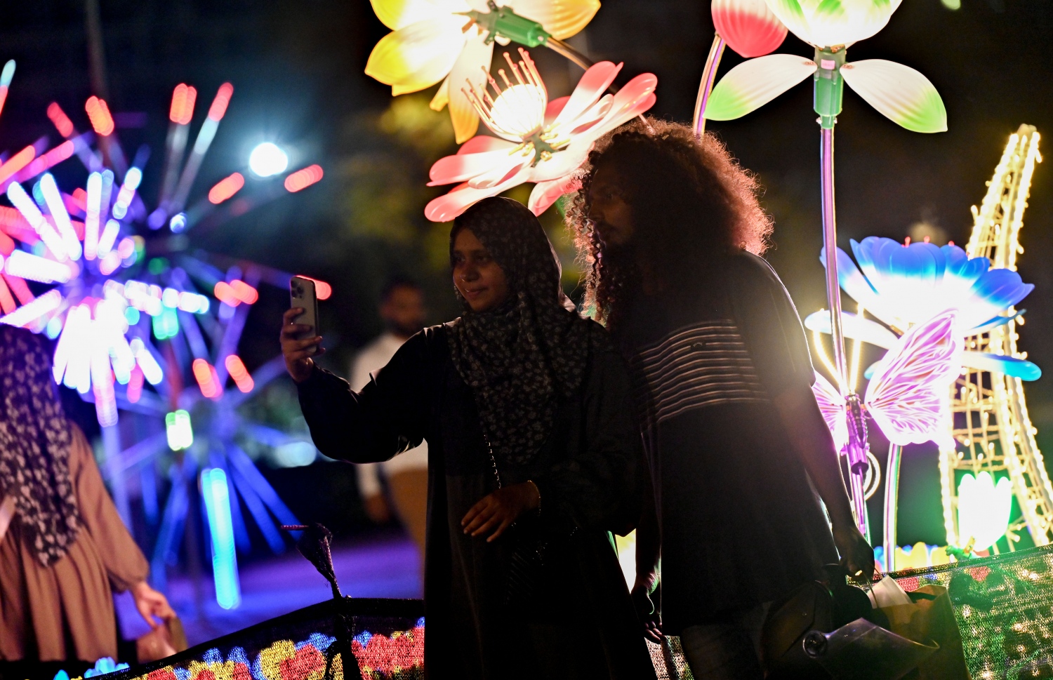 ފިތުރު އީދަށް ހުޅުމާލޭގެ އެކި ސަރަހައްދުތައް ކުލަ ބޮކިތަކާއި ޑިޒައިންތަކުން ޒީނަތްތެރިކޮށްފައި ހުރި އިރު ބަޔަކު އެތަނުގެ ކައިރީގައި ފޮޓޯ ނަގަނީ. -- ފޮޓޯ: ނިޝާން އަލީ | މިހާރު