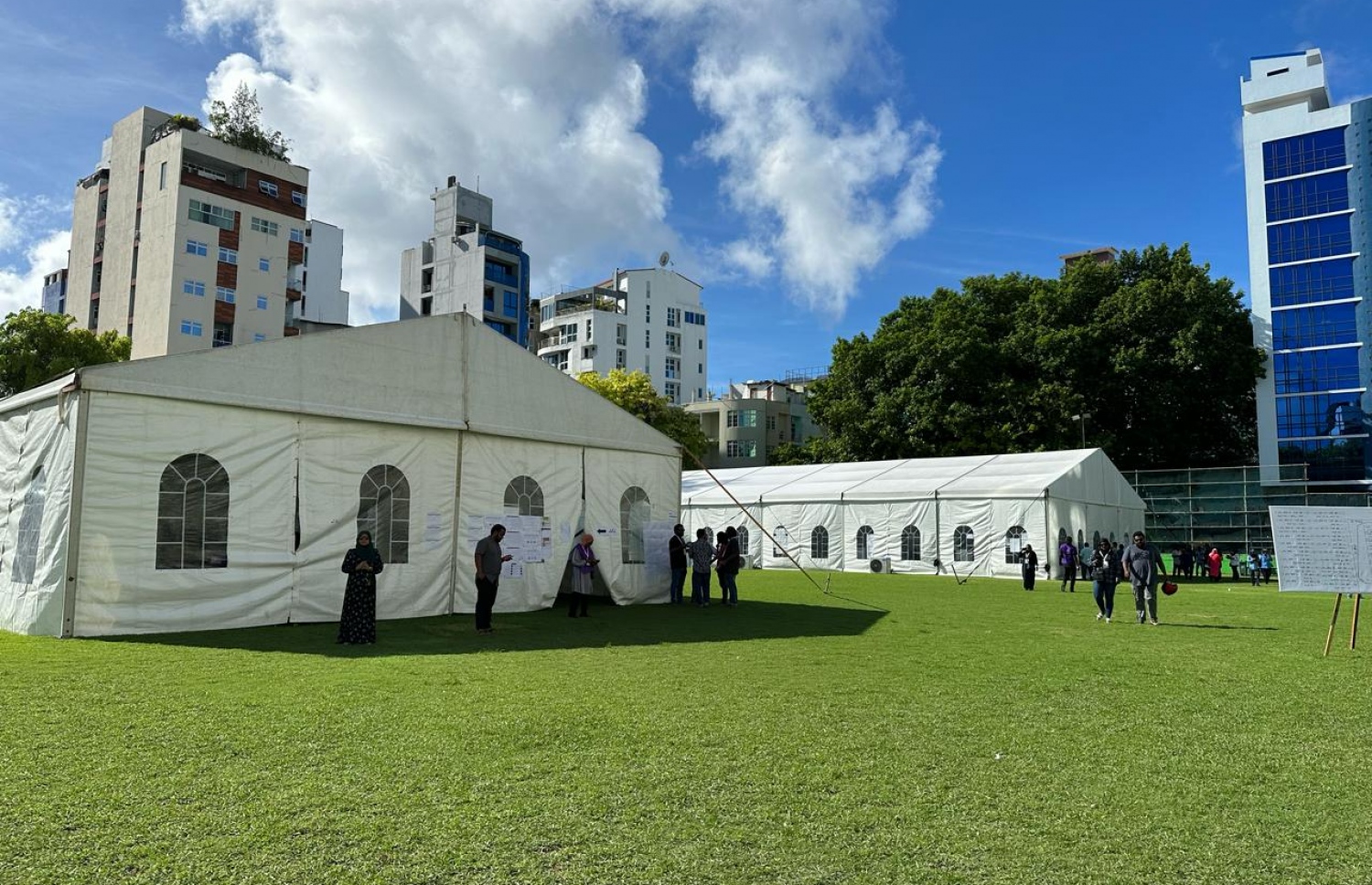 ބައެއް ރަށްރަށުގެ މީހުން ވޯޓުލުމަށްޓަކައި ހެންވޭރު ދަނޑުގައި ބަހައްޓާފައިވާ ޓެންޓުތަކުގެ ބޭރުގައި ބަޔަކު ހަރަކާތްތެރިވަނީ.---ފޮޓޯ: މާއިދާ ރަޝާދު| މިހާރު