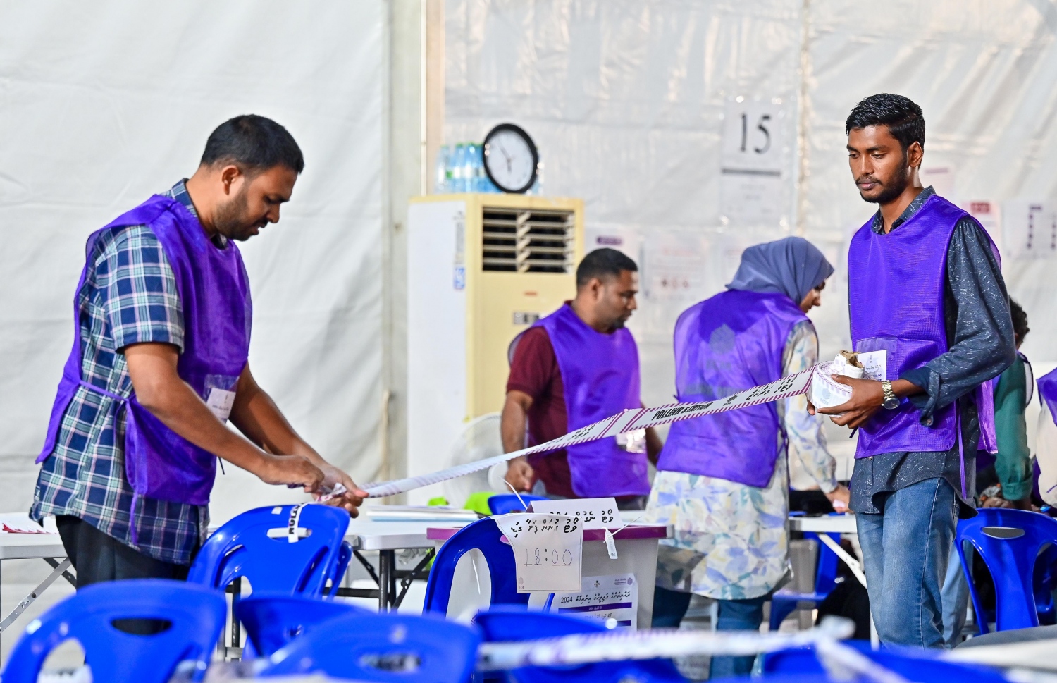 ވިހި ވަނަ ރައްޔިތުންގެ މަޖިލިހުގެ އިންތިހާބުގެ ވޯޓު ލުމުގެ ކިއު ބަންދު ކުރުމަށް ފަހު ވޯޓުފޮއްޓެއްގެ ކައިރީގައި އިލެކްޝަންސް ކޮމިޝަންގެ އޮފިޝަލުންތަކެއް ހަރަކާތްތެރިވަނީ.---ފޮޓޯ: ފަޔާޒު މޫސާ| މިހާރު