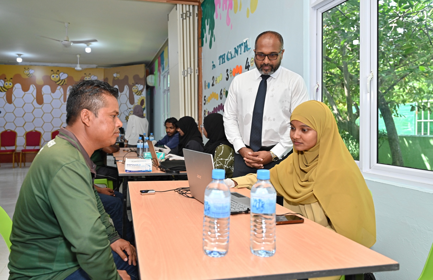 ބިދޭސީންގެ ފިންގަޕްރިންޓާއި ފޮޓޯ ނެގުމުގެ ގައުމީ ކެމްޕެއިން، "ކުރަނގި" ފެށުމަށްފަހު، ބިދޭސީއަކު ފިންގަޕްރިންޓު ޖަހާއިރު  ހޯމް ލޭންޑު ސެކިއުރިޓީ މިނިސްޓަރު އިހުސާން މަޑުކޮށްލައްވައިގެން.-- ފޮޓޯ: ނިޝާން އަލީ/ މިހާރު