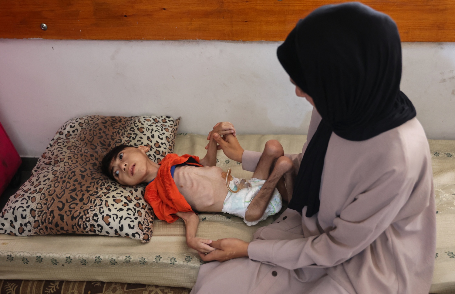 ޣައްޒާގައި ރަނގަޅަށް ކާނާ ނުލިބިގެން ހާލު ދެރަވެފައިވާ ކުއްޖެއްގެ ކައިރީގައި އޭނާގެ މަންމަ އިށީނދެލައިގެން. --ފޮޓޯ: އޭއެފްޕީ