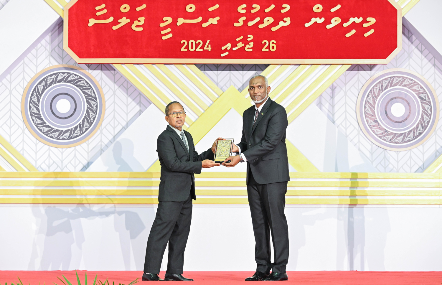 ދިވެހި ދައުލަތަށް ދިގު މުއްދަތަކަށް ހިދުމަތް ކުރެއްވި ބޭފުޅެއްގެ ހިދުމަތުގެ އަގު ވަޒަން ކުރައްވައި، ރައީސް މުއިއްޒު ޝަރަފުގެ ބެޖާއި އައްޑަނަ ދެއްވަނީ.--- ފޮޓޯ: ރައީސް އޮފީސް