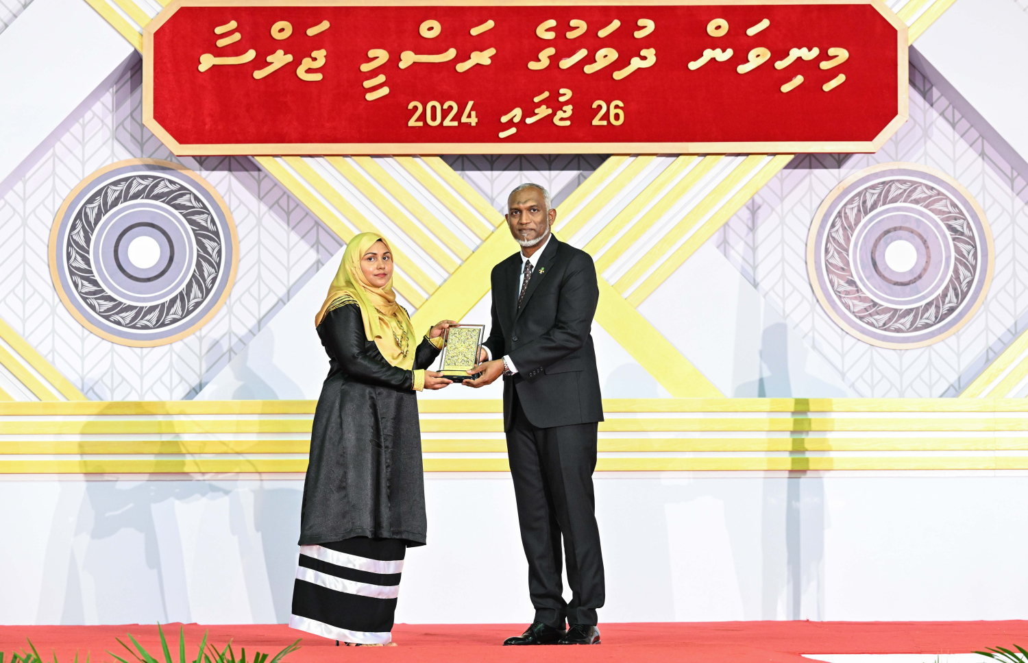 ދިވެހި ދައުލަތަށް ދިގު މުއްދަތަކަށް ހިދުމަތް ކުރެއްވި ބޭފުޅެއްގެ ހިދުމަތުގެ އަގު ވަޒަން ކުރައްވައި، ރައީސް މުއިއްޒު ޝަރަފުގެ ބެޖާއި އައްޑަނަ ދެއްވަނީ.--- ފޮޓޯ: ރައީސް އޮފީސް