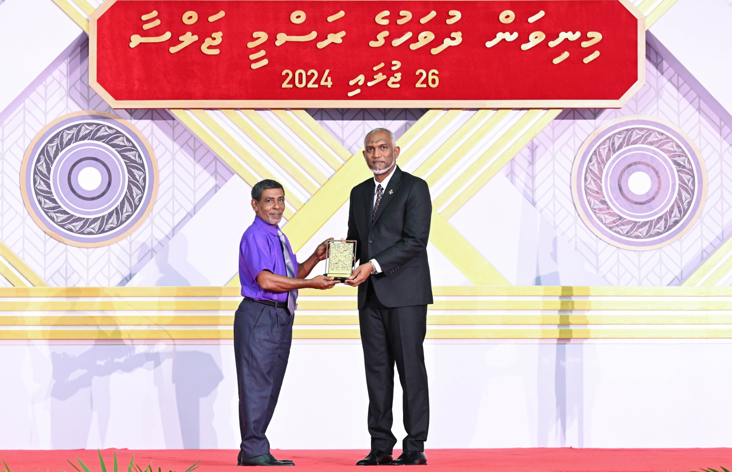 ދިވެހި ދައުލަތަށް ދިގު މުއްދަތަކަށް ހިދުމަތް ކުރެއްވި ބޭފުޅެއްގެ ހިދުމަތުގެ އަގު ވަޒަން ކުރައްވައި، ރައީސް މުއިއްޒު ޝަރަފުގެ ބެޖާއި އައްޑަނަ ދެއްވަނީ.--- ފޮޓޯ: ރައީސް އޮފީސް