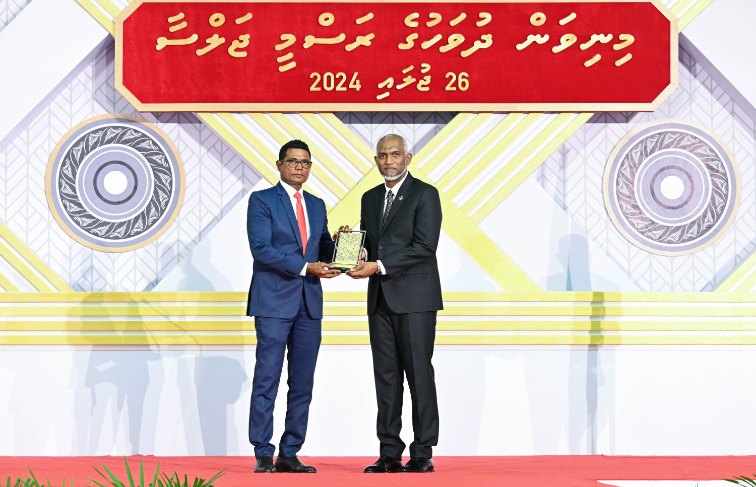 ދިވެހި ދައުލަތަށް ދިގު މުއްދަތަކަށް ހިދުމަތް ކުރެއްވި ބޭފުޅެއްގެ ހިދުމަތުގެ އަގު ވަޒަން ކުރައްވައި، ރައީސް މުއިއްޒު ޝަރަފުގެ ބެޖާއި އައްޑަނަ ދެއްވަނީ.--- ފޮޓޯ: ރައީސް އޮފީސް