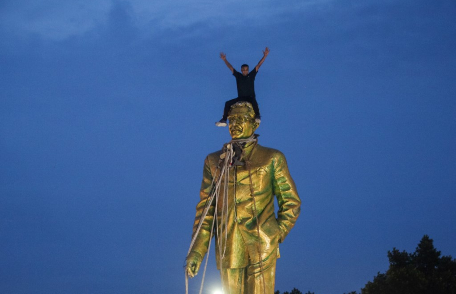 ބަންގްލާދޭޝްގެ ބާނީ، ޝައިހް ހަސީނާގެ ބައްޕާފުޅުގެ ބުދު ވައްޓާލަން މުޒާހަރާގެ ބައިވެރިން މަސައްކަތްކުރާއިރު އެކަކު ބުދުގެ މައްޗަށް އަރައި އުފާ ފާޅުކުރަނީ. -- ފޮޓޯ: އޭއެފްޕީ