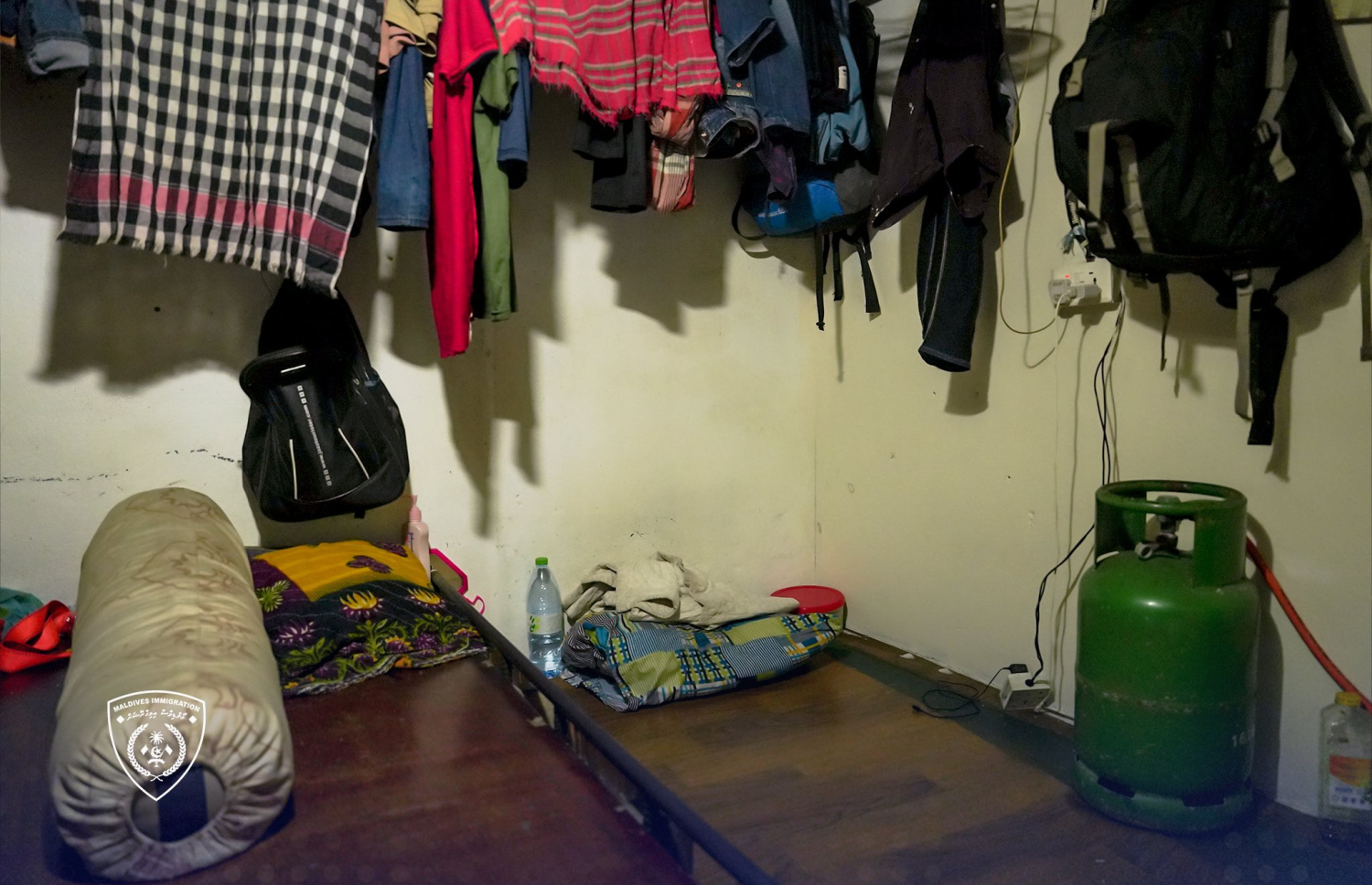 ބިދޭސީން ދިރިއުޅޭ ގެއެއްގައި މީހަކު ނިދާ އެނދެއްގެ މަތީގައި ގޭސްފުޅިއެއް ބަހައްޓައިފައި.-- ފޮޓޯ: އިމިގްރޭޝަން