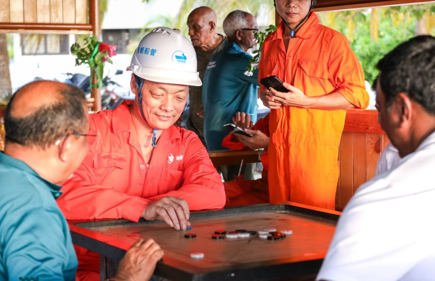 އުތުރު މެރިޓައިމް ސާވިސް (ޔޫއެމްސީ)ގެ ހިދުމަތް ހޯދުމަށް ރާއްޖެ އައި ޕެނަމާގެ ބޯޓުގެ ފަޅުވެރިން އެމްޕީއެލްގެ އިސްވެރިންނާ އެކު އުލިގަމުގައި ކެރަމް ކުޅެނީ.-- ފޮޓޯ: އެމްޕީއެލް