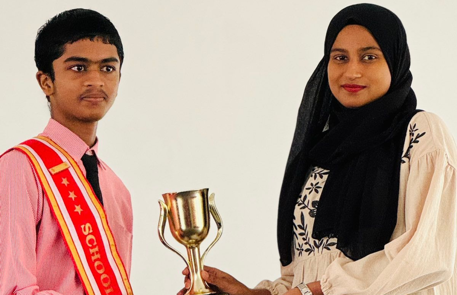 އެ ސްކޫލުގެ ލީޑިން ޓީޗަރު އައިމިނަތު މާޖިދާ، ޣައިސް އަށް ޓްރޮފީއެއް ހަވާލުކުރަނީ.