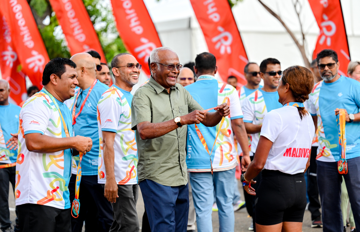 ރާއްޖޭގައި ބާއްވާ ދުވުމުގެ އެންމެ ބޮޑު ރޭސް، ދިރާގު މޯލްޑިވްސް ރޯޑް ރޭހުގެ ބައިވެރިޔަކު ރޭސް ނިންމުމުން ކަރުގައި މެޑަލް އަޅުވަނީ.--- ފޮޓޯ: ނިޝާން އަލީ | މިހާރު