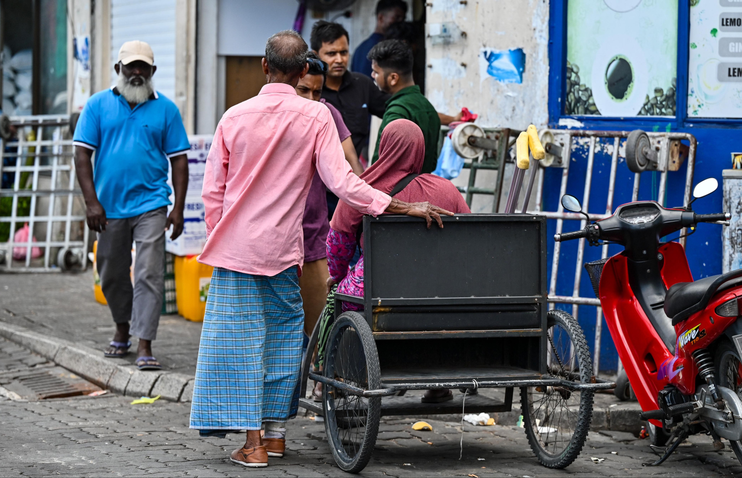 ގަފޫރުގެ ދެމަފިރިން ބާޒާރުމަތީގައި އެމީހުންގެ ވާހަކަ ކިޔައިދެނީ. -- ފޮޓޯ: ފަޔާޒު މޫސާ | މިހާރު