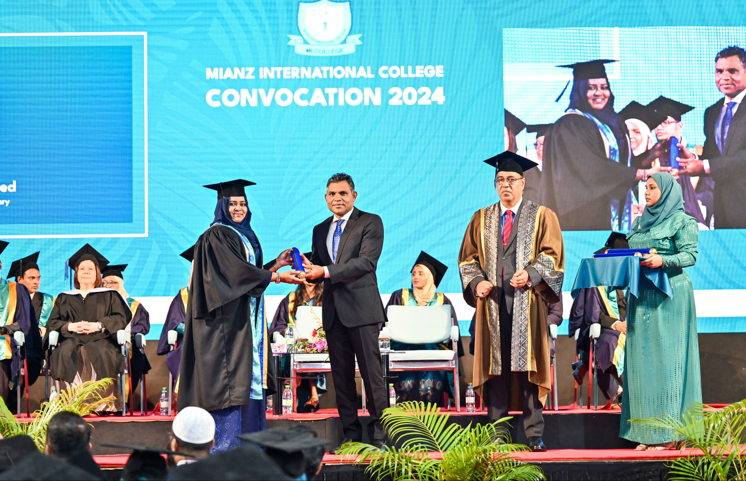 އެމްއައި ކޮލެޖުން މި އަހަރު ގްރެޖުއޭޓްވި ދަރިވަރަކާ ކުރީގެ ނައިބު ރައީސް ފައިސަލް ސެޓްފިކެޓް ހަވާލު ކޮށްދެއްވާއިރު، އަރިހުގައި އެ ކޮލެޖުގެ ޗެއާމަން އަހުމަދު މޮއްޓާކީ.--- ފޮޓޯ: ފަޔާޒު މޫސާ | މިހާރު