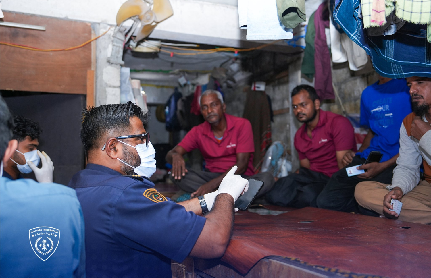 އިމިގްރޭޝަނުން ރޭ ބަލައި ފާސް ކުރި ތަންތަނުގައި ދިރިއުޅުނު ބިދޭސީންނާ އިމިގްރޭޝަންގެ އޮފިސަރަކު ވާހަކަ ދައްކަނީ.-- ފޮޓޯ: އިމިގްރޭޝަން