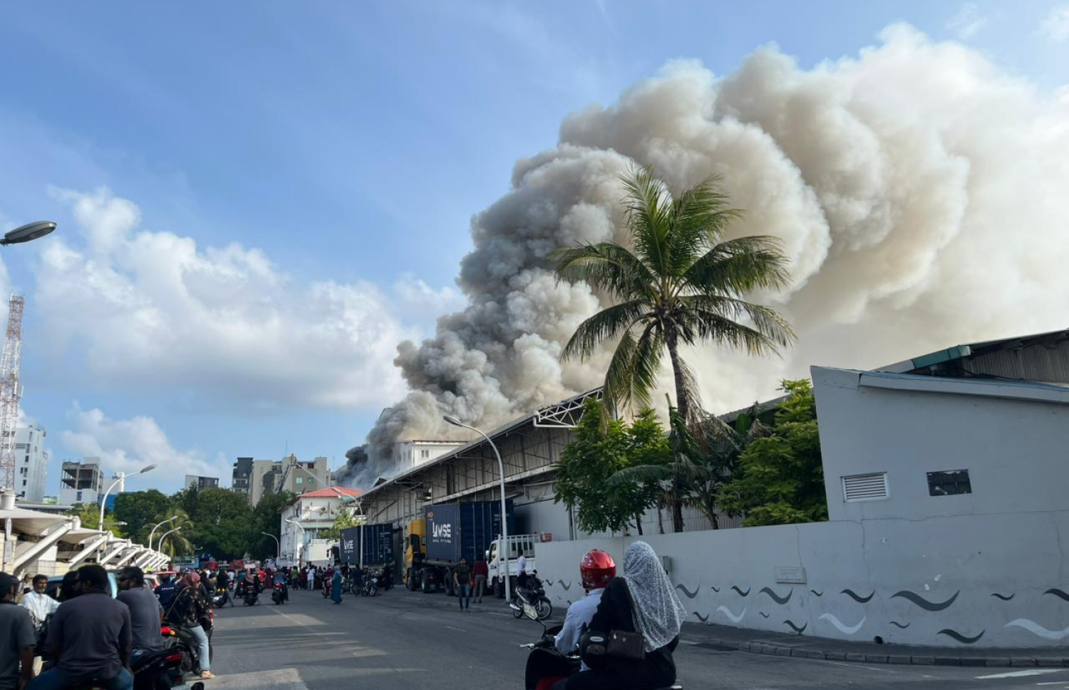 ސަރުކާރުގެ މުހިންމު ގިނަ އޮފީސްތަކެއް ހިންގާ މ. ގްރީން ބިލްޑިންގައި ރޯވެ އަނދާއިރު، ބަޔަކު އެ މަންޒަރު ބަލަން މަގުމަތީގައި މަޑުކޮށްލައިގެން: އެ އިމާރާތުގައި މަސައްކަތްކުރާ ބައެއް މުވައްޒަފުން ވެސް އެތަނުގައި ތިބި.-- ފޮޓޯ: މިހާރު