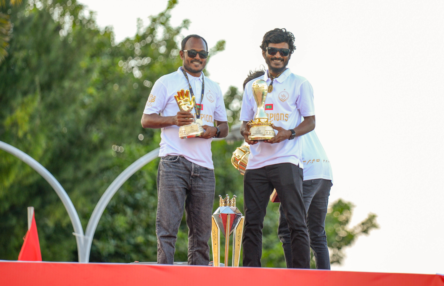 ނައިންޓީ ޕްލަސް ގޯލްޑް ކަޕް ކާމިޔާބުކުރި ބ. އޭދަފުށި ފުޓްބޯޅަ ޓީމު އިއްޔެ ހަވީރު އެރަށަށް ދިއުމުން ކުރިއަށް ގެންދިޔަ ޕެރޭޑްގައި، މުބާރާތުގެ މޮޅު ކުޅުންތެރިޔާ މުހައްމަދު ފާސިރު (ކ) އަދި އެންމެ މޮޅު ގޯލްކީޕަރު އަބްދުﷲ ޒިޔަޒަން (ވ).--- ފޮޓޯ: އަހުމަދު ޔާނިއު