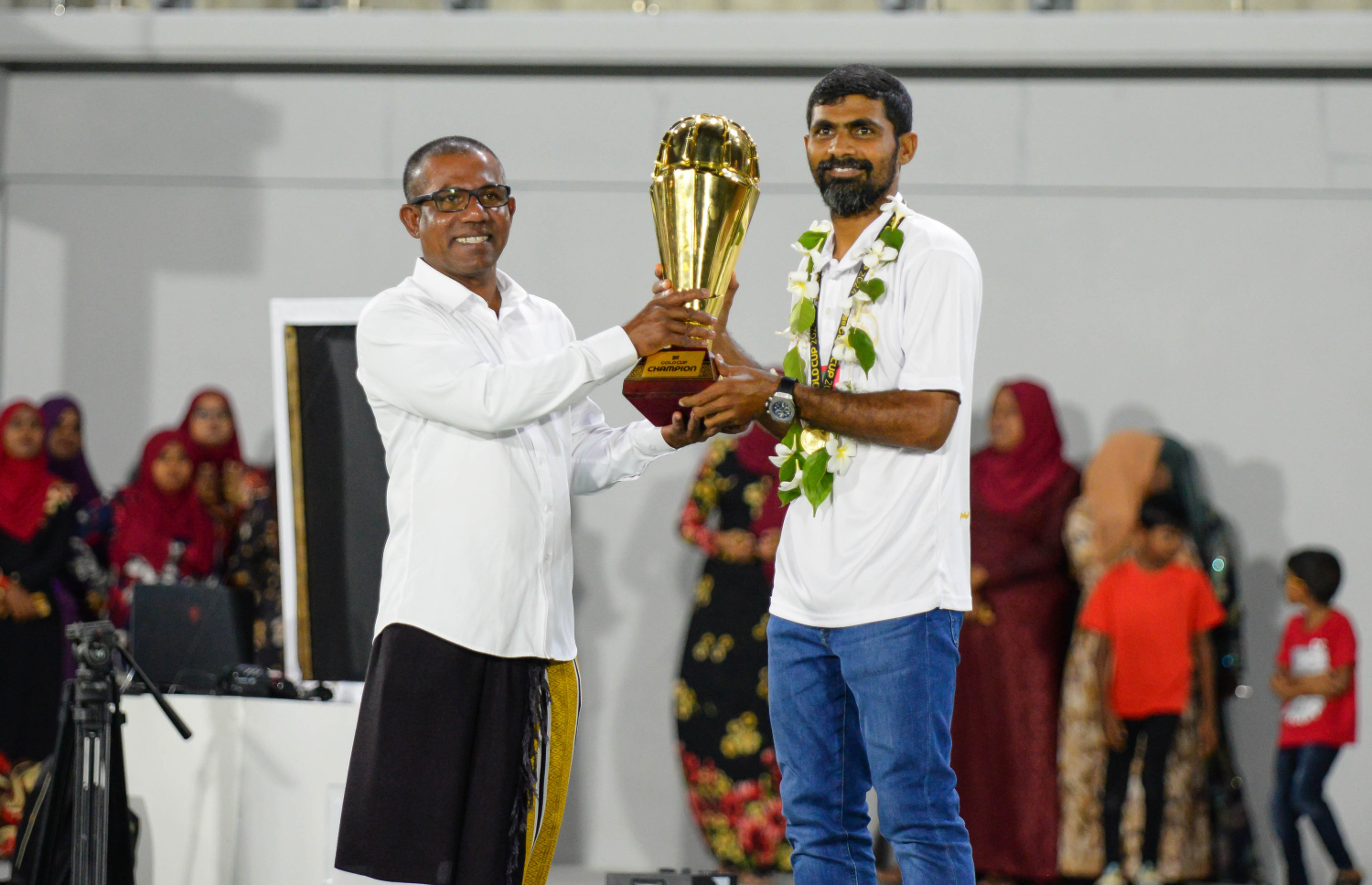 އޭދަފުށި ޓީމުގެ ކެޕްޓަން އިޝާން އަދި ރަށު ކައުންސިލްގެ ރައީސް މުހައްމަދު ފާތިހް، ގޯލްޑް ކަޕްގެ ޗެމްޕިއަން ޓްރޮފީ ހިފައިގެން.--- ފޮޓޯ: އަހުމަދު ޔާނިއު