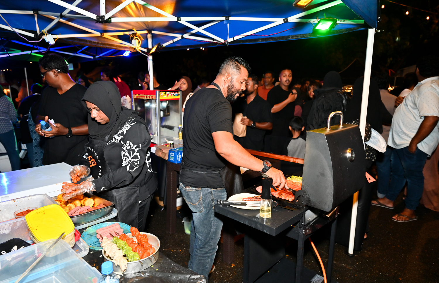 ރާއްޖެ އިން 2025 ވަނަ އަހަރަށް މަރުހަބާ ކިޔަން މޯލްޑިވްސް ކަލްޗާ އެންޑް ފުޑް ފެސްޓިވަލްގެ ނަމުގައި ސެންޓްރަލް ޕާކުގައި ކުރިއަށް ގެންދާ ހަރަކާތުގައި ބަހައްޓާފައިވާ ސްޓޯލެއްގެ ކައިރީގައި ބަޔަކު ހަރަކާތްތެރިވަނީ.---ފޮޓޯ: ނިޝާން އަލީ| މިހާރު