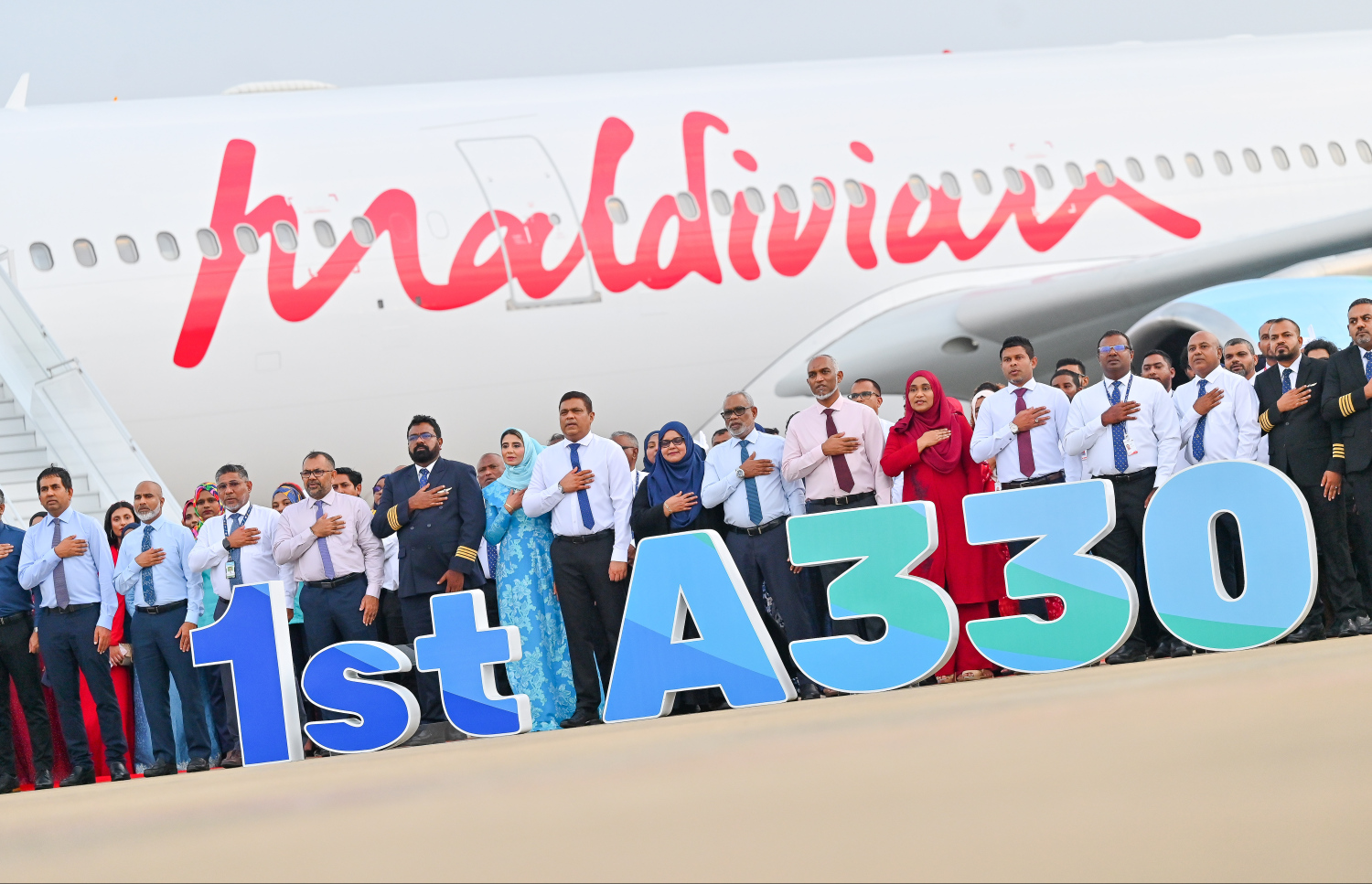 ރާއްޖޭގެ ގައުމީ އެއާލައިން މޯލްޑިވިއަން އަށް ގެނައި އެއާބަސް އޭ330 ބޯޓު ނުވަތަ އެ އެއާލައިންގެ ފުރަތަމަ ވައިޑް-ބޮޑީ އެއާކްރާފްޓް ކައިރީގައި ތިއްބަވައިގެން ރައީސް މުއިއްޒުގެ ދެކަނބަލުންނާއި ސަރުކާރުގެ ބައެއް އިސްވެރިން ގައުމީ ސަލާން ވިދާޅުވަނީ.---ފޮޓޯ: ނިޝާން އަލީ| މިހާރު