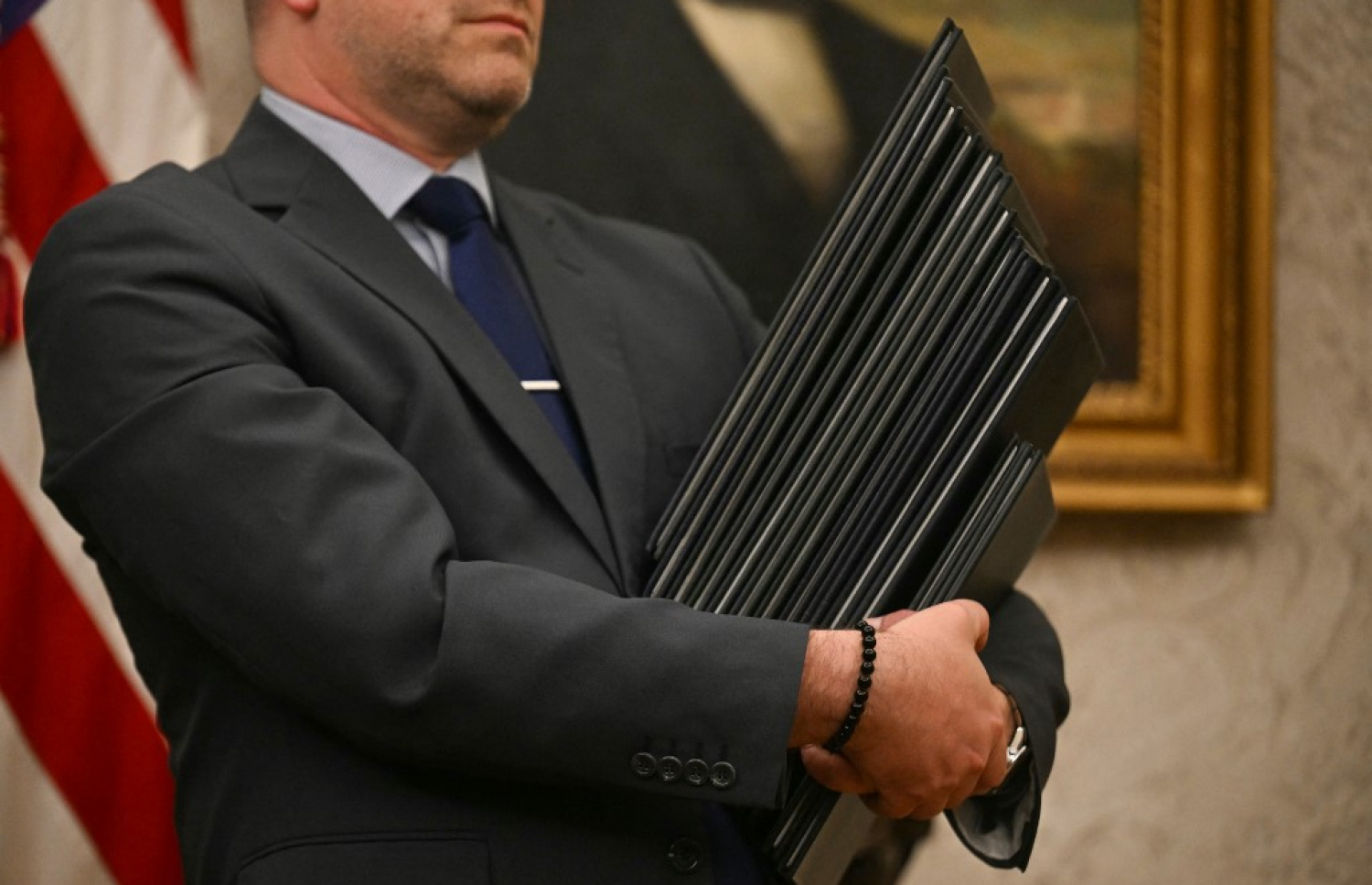 އެމެރިކާގެ ރައީސްކަމުގެ މަގާމާ ދެ ވަނަ ފަހަރަށް ހަވާލުވެ ވަޑައިގަތުމަށް ފަހު، ވެރިކަމުގެ ފުރަތަމަ ދުވަހު ޑޮނަލްޑް ޓްރަމްޕް ސޮއިކުރައްވަން ނިންމަވާފައިވާ ގަރާރުތައް ހިމެނޭ ފައިލްތަކާ އެކު ވައިޓް ހައުސްގެ މުވައްޒަފަކު ޓްރަމްޕުގެ އަރިހުގައި ހުއްޓިގެން. -- ފޮޓޯ: އޭއެފްޕީ