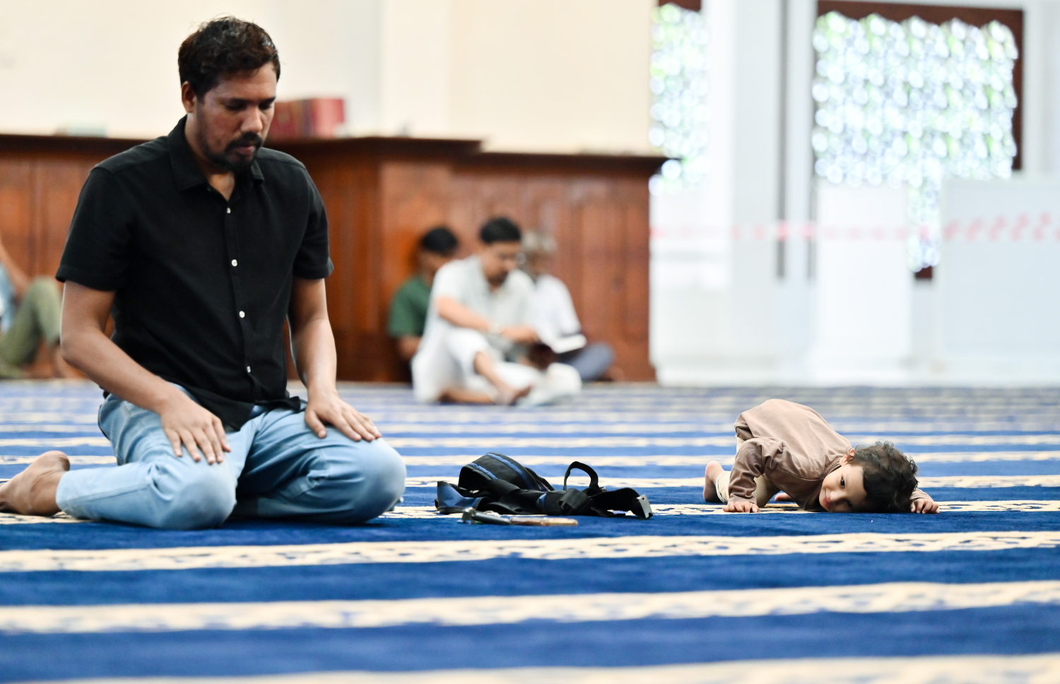 މި ރޯދަމަހު އިސްލާމީ މަރުކަޒުގައި މީހަކު ނަމާދުކުރާއިރު ކުޑަކުއްޖަކު ބަލަހައްޓައިގެން.---ފޮޓޯ: ނިޝާން އަލީ| މިހާރު