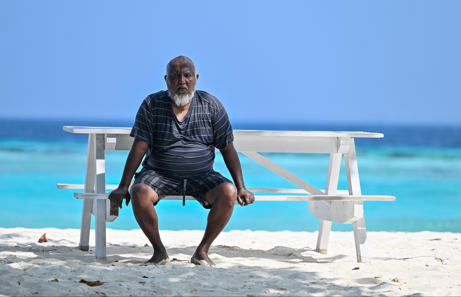 ކޭމްޕްގެ ބައިވެރިއަކު ބީޗުގައި ހުރި ބެންޗެއްގައި އިށީނދެލައިގެން: މި ކޭމްޕެގެ ބައިވެރިން ގަޑި ޖެހުމުގެ މާ ކުރިން ތިބެނީ މިތަނަށް ޖަމާވެފަ އެވެ.