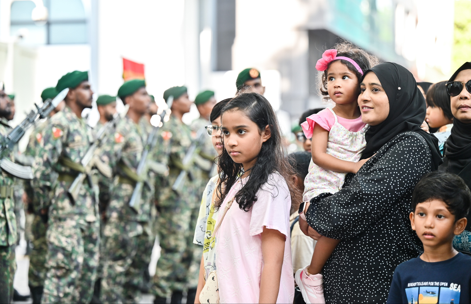 ސިފައިންގެ ޕެރޭޑް ބެލުމަށް ރައީސް އޮފީސް ކައިރީގައި ކުޑަކުދިންތަކެއް ގޮވައިގެން މީހަކު މަޑުކޮށްލައިގެން.--- ފޮޓޯ: ފަޔާޒު މޫސާ | މިހާރު