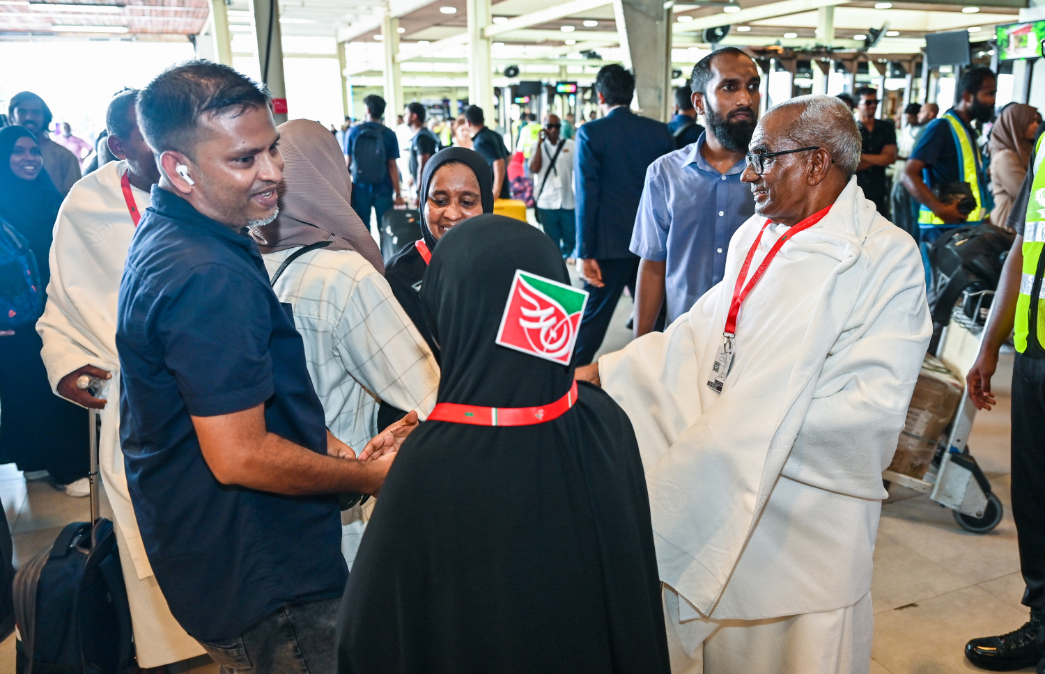 ރާއްޖެ އިން މި އަހަރު ހައްޖަށް ދާ މީހުންގެ ފުރަތަމަ ގުރޫޕުގައި ހިމެނޭ ބަޔަކު ފުރުމަށްޓަކައި އެއާޕޯޓުގެ ޓާމިނަލަށް ވަނުމުގެ ކުރިން އާއިލާ މީހުންނާ ސަލާން ކުރަނީ.---- ފޮޓޯ: ފަޔާޒު މޫސާ | މިހާރު