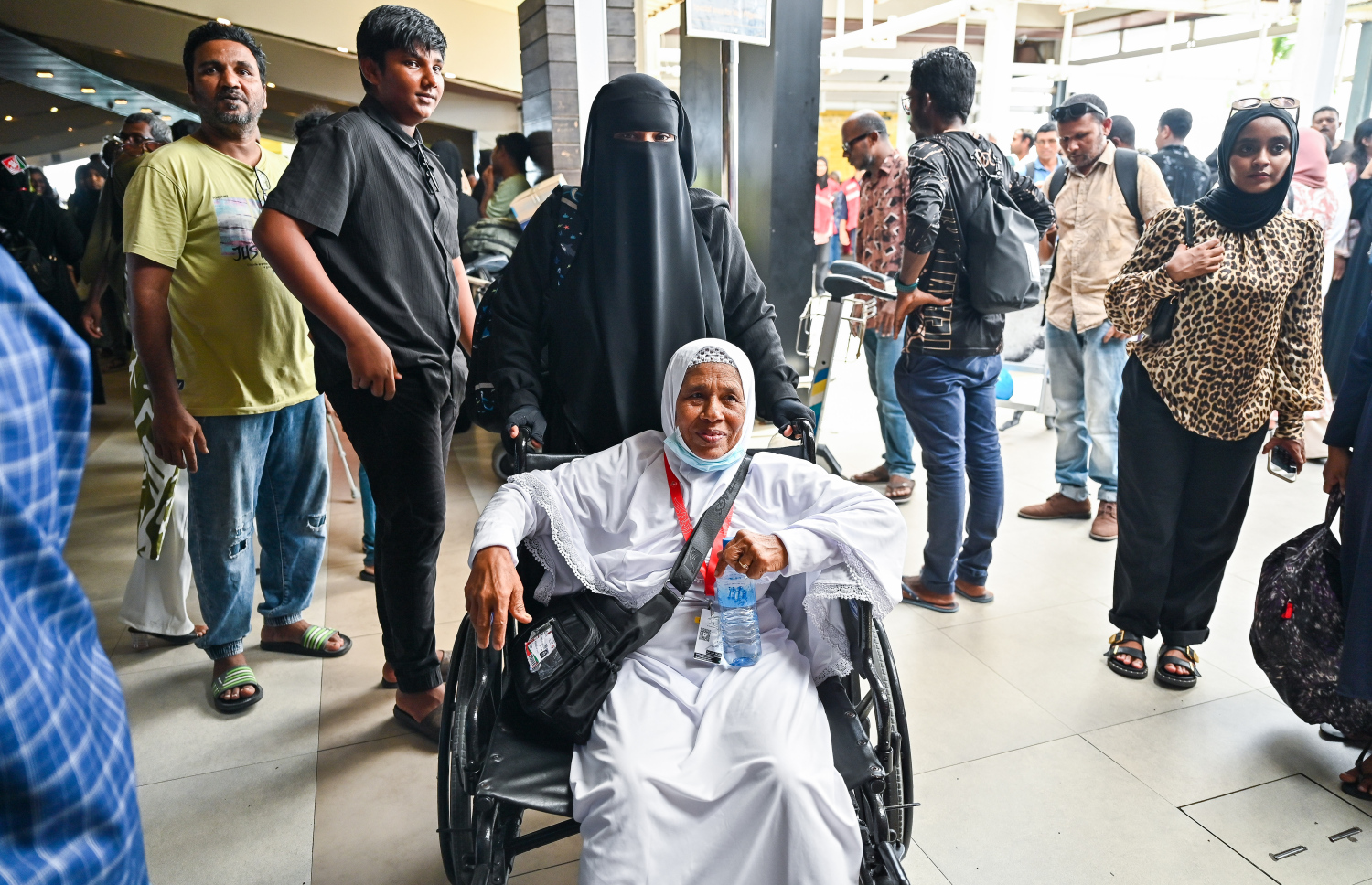 ރާއްޖެ އިން މި އަހަރު ހައްޖަށް ދާ މީހުންގެ ފުރަތަމަ ގުރޫޕުގައި ހިމެނޭ އުމުރުން ދުވަސްވީ އަންހެނަކު އެއާޕޯޓުގެ ޓާމިނަލަށް ވަންނަނީ.--- ފޮޓޯ: ފަޔާޒު މޫސާ | މިހާރު