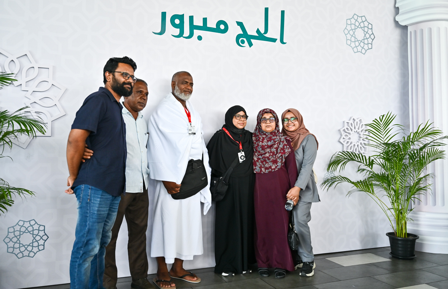 ރާއްޖެ އިން މި އަހަރު ހައްޖަށް ފުރި ފުރަތަމަ ގުރޫޕުގެ ދެ މީހަކު އާއިލާގެ ބަޔަކާ އެކު ވެލާނާ އިންޓަނޭޝަނަލް އެއާޕޯޓުގައި ފޮޓޯއެއް ނަގަނީ.--- ފޮޓޯ: ފަޔާޒު މޫސާ | މިހާރު