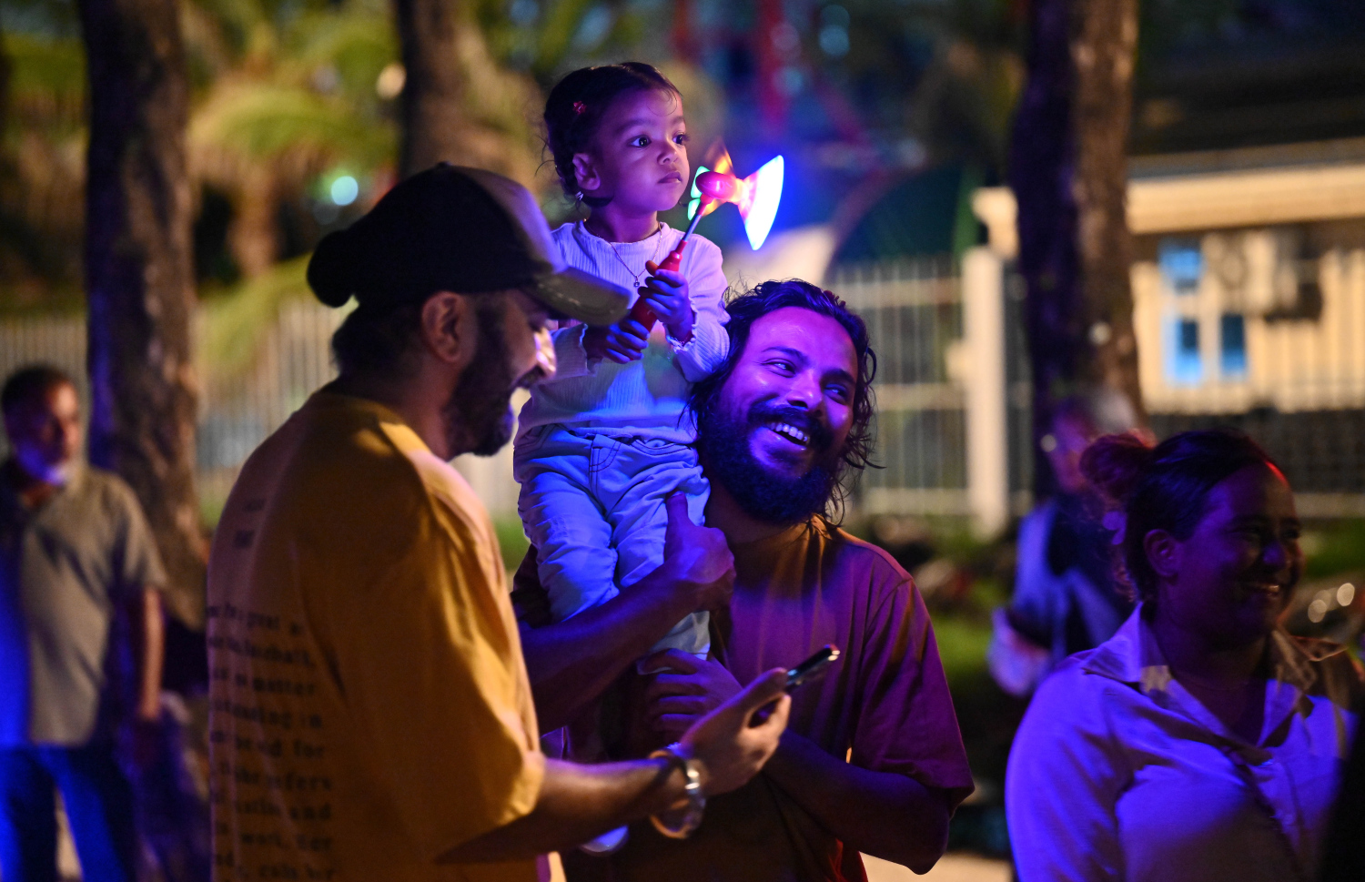 ބޮޑު އީދަށް މަރުހަބާ ކިޔުމަށް ހުޅުމާލޭގައި އީދު މަޅި ރޯކުރުމަށް މިރޭ ބޭއްވި ހަރަކާތް ބަލަން ދިޔަ ބައެއް މީހުން ކުޑަކުއްޖަކު އުރާލައިގެން.---ފޮޓޯ: ނިޝާން އަލީ| މިހާރު