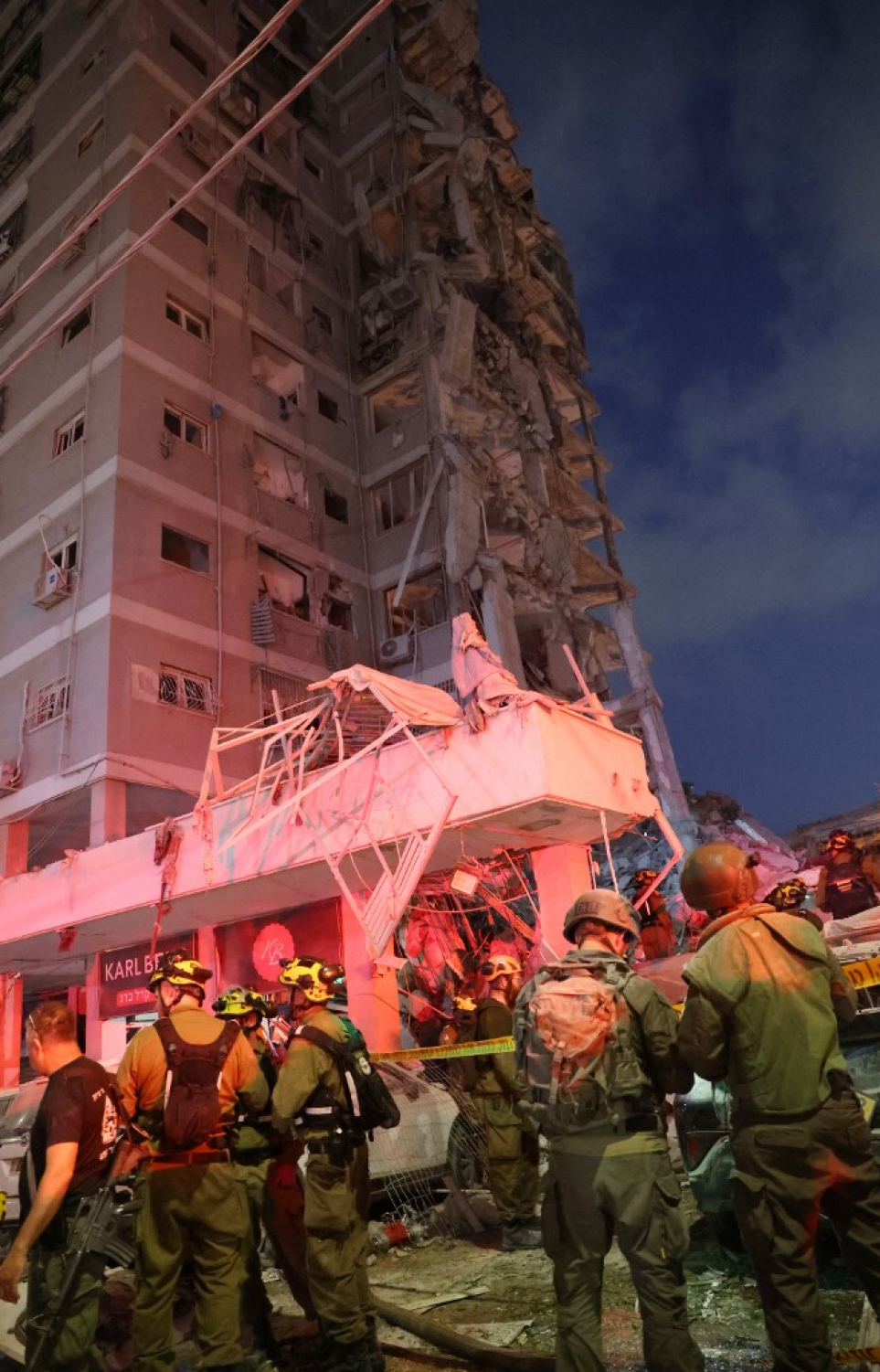 އީރާންގެ ހަމަލާއެއްގައި އިޒްރޭލުން ހަލާކުވި އިމާރާތެއްގެ ކައިރީ ސިފައިންގެ ބަޔަކު މަޑުކޮށްލައިގެން: ރޭގެ ހަމަލާތަކުގައި އެތައް ބަޔަކު އިޒްރޭލުން މަރުވި އިރު އެތައް ސަތޭކަ ބަޔަކު ވަނީ ޒަހަމްވެފައި. -- ފޮޓޯ: އޭއެފްޕީ