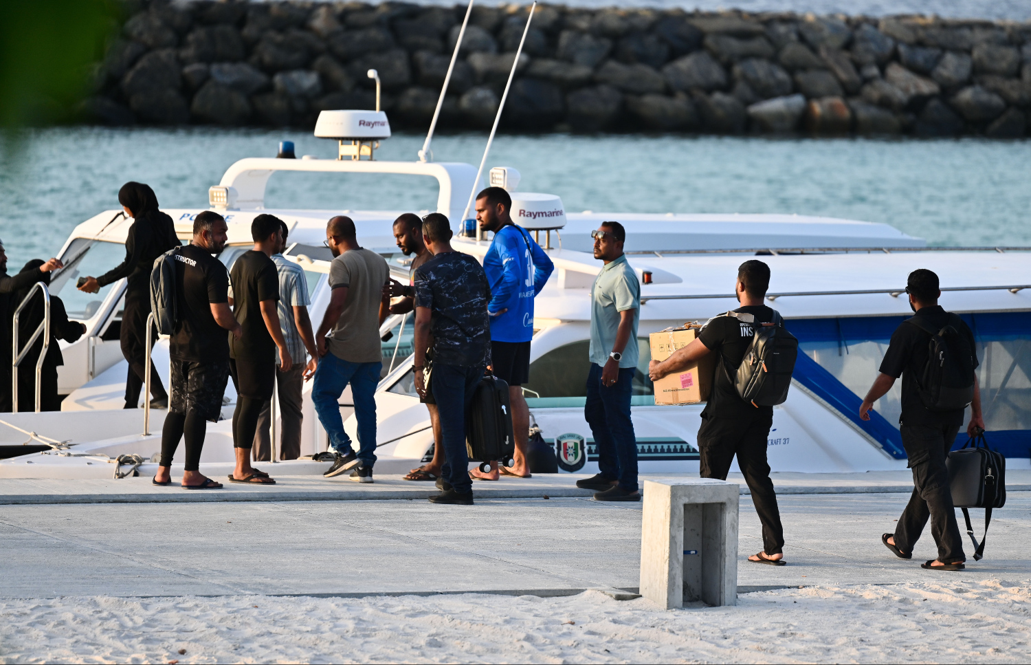 މިދިޔަ ހޮނިހިރު ދުވަހުގެ ރޭ ދަންވަރު ދިން އަނިޔާވެރި ހަމަލައާ ގުޅިގެން މަރުވި މާޅޮހު އޯކިޑްމާގޭ އުމުރުން 65 އަހަރުގެ އަބްދުއްރަހުމާން އާދަމް މަރުގެ މައްސަލަ ތަހުގީގު ކުރުމަށް މި ރަށުގައި ހަރަކާތްތެރިވި ފުލުހުންގެ ތަހުގީގު ޓީމުގެ ބައެއް މީހުން ފުރަން ލޯންޗަށް އަރަނީ.--- ފޮޓޯ: ފަޔާޒު މޫސާ | މިހާރު