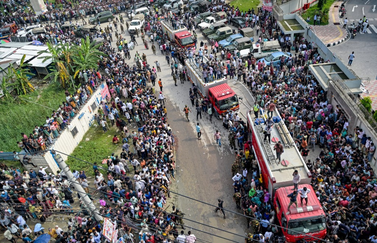 ބަންގްލާދޭޝްގައި ސްކޫލެއްގެ ތެރެއަށް ޖެޓެއް ވެއްޓުނު ހާދިސާއަށް ފަހު އިމަޖެންސީ ވެހިކަލްތައް ޖަމާވަނީ އަދި އެ ހިސާބަށް މީހުން އެއްވެފައި. -- ފޮޓޯ: އޭއެފްޕީ