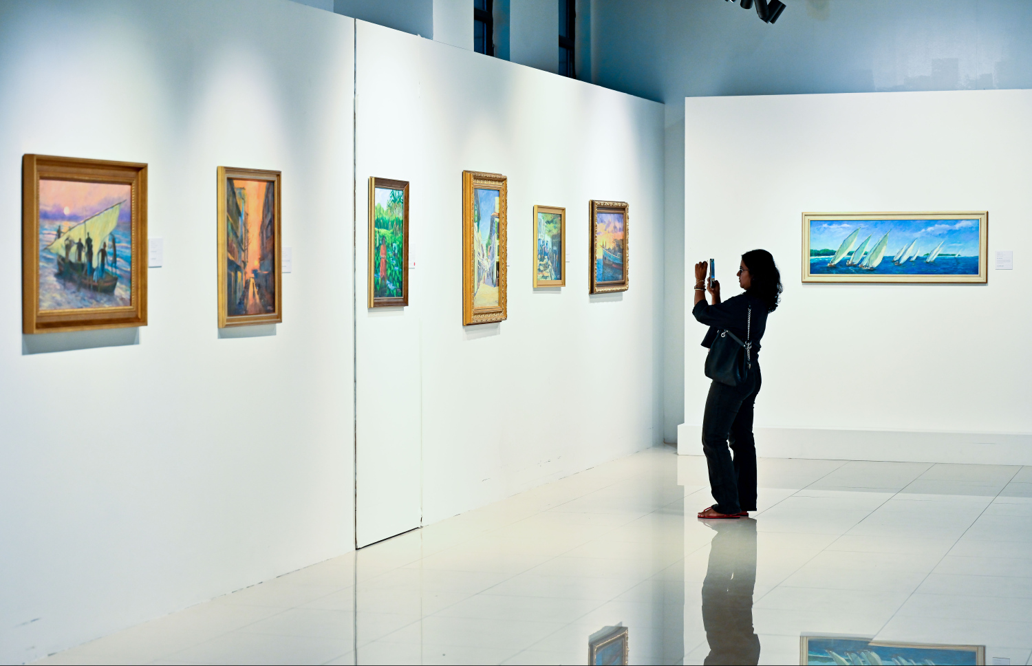 ރާއްޖޭގެ އެހާރާއި މިހާރުގެ ދިރިއުޅުން ދައްކުވައިދޭ ކުރެހުންތަކާ އެކު، އާޓް ގެލެރީގައި މިހާރު ކުރިއަށް ގެންދާ މަނާގޭ އަބްދުﷲ ފާއިޒުގެ ކުރެހުމުގެ މައުރަޒަށް ޒިޔާރަތްކުރި ޒުވާނަކު ކުރެހުމުގެ ފޮޓޯއެއް ނަގަނީ: މި މަހުގެ 16 އިގެ ނިޔަލަށް މި މައުރަޒު ކުރިއަށް ގެންދާނެ.---ފޮޓޯ: ނިޝާން އަލީ| މިހާރު